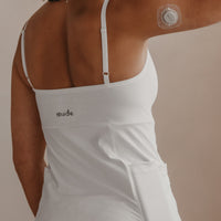 Woman wearing a white Mude Camisole top with 'Mude' branding, showing a CGM on their arm.