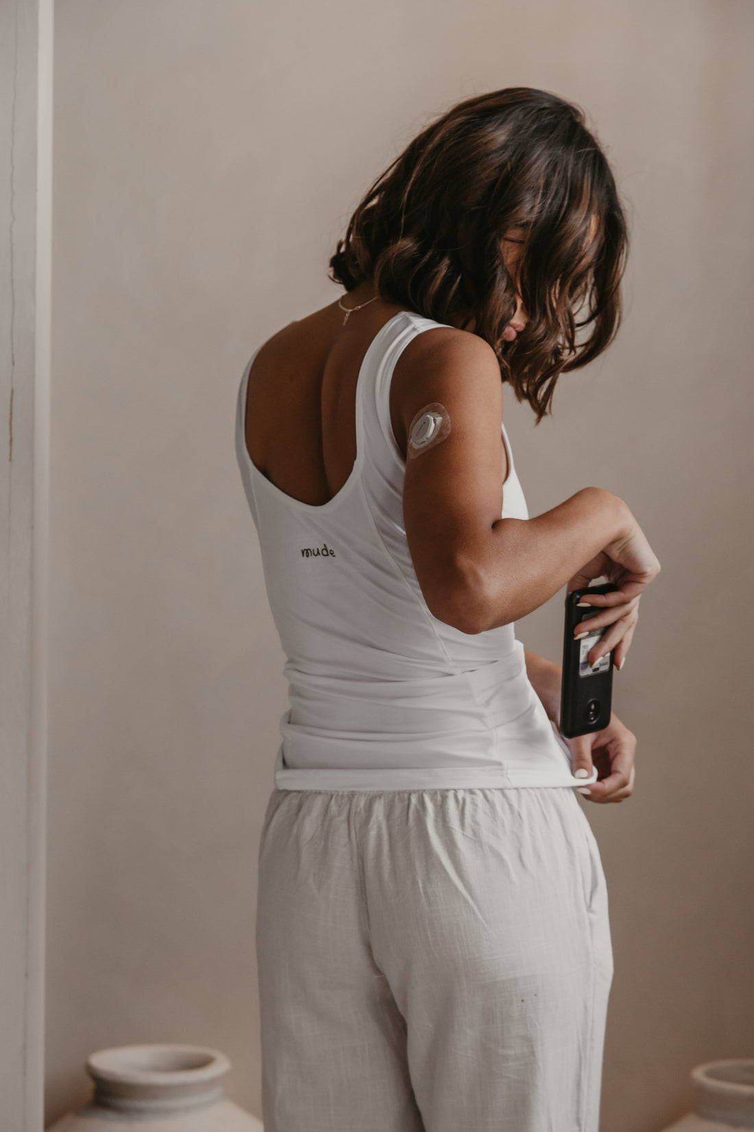 Woman putting her Omnipod controller into her white Mude Tank waist pocket