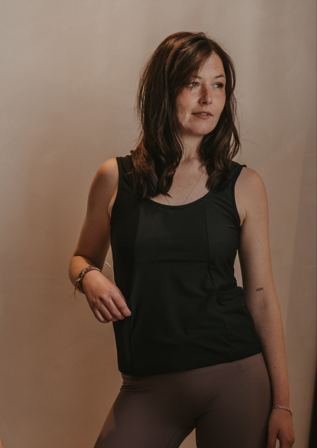 Woman wearing a black Mude Tank top against a beige background